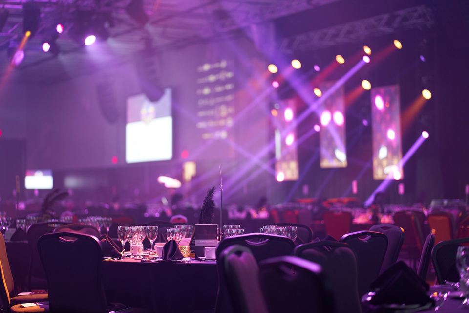 Ballroom set for a corporate dinner, with LED screens and purple stage lighting