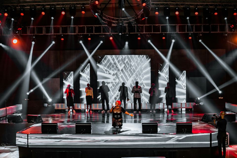Stage with an LED wall and moving-light beams cutting through haze